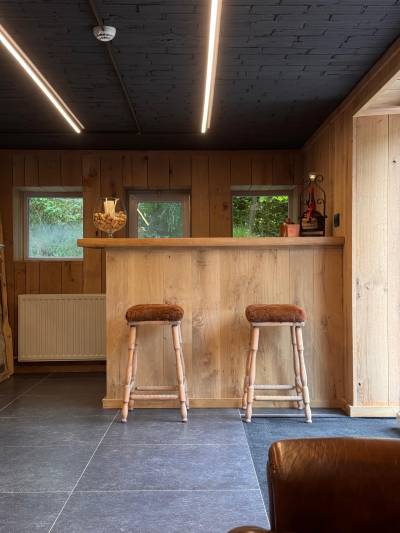Bar entièrement en bois avec tabourets assortis et petit réfrigérateur.