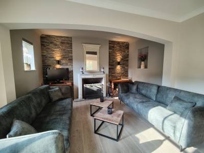 Le salon chaleureux, avec cheminée, sièges moelleux et beau mur en pierre.
