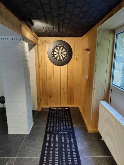 Cible de fléchettes professionnelle avec tapis personnalisé monté sur un mur en bois.
