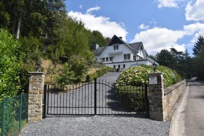 Belle porte ornementale qui ferme le domaine avec vue sur la maison.