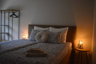 Lit fait dans la chambre 4 avec une belle armoire ouverte industrielle, des tables de chevet en bois et des lampes chaleureuses.