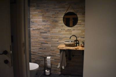 Lavabo avec plan en bois, vasque en pierre et miroir.